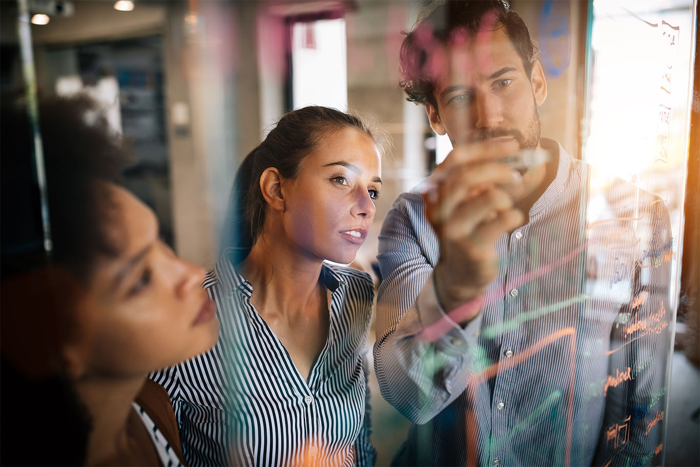 Image of a professional group of people gathered round a board with words written on it to support strategic management process listicle