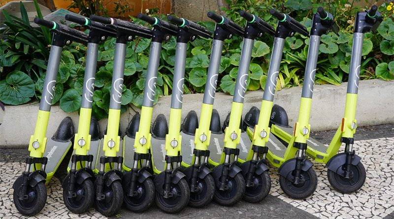 Image of yellow and black push scooters lined up in a row in a park to support superpedestrian article
