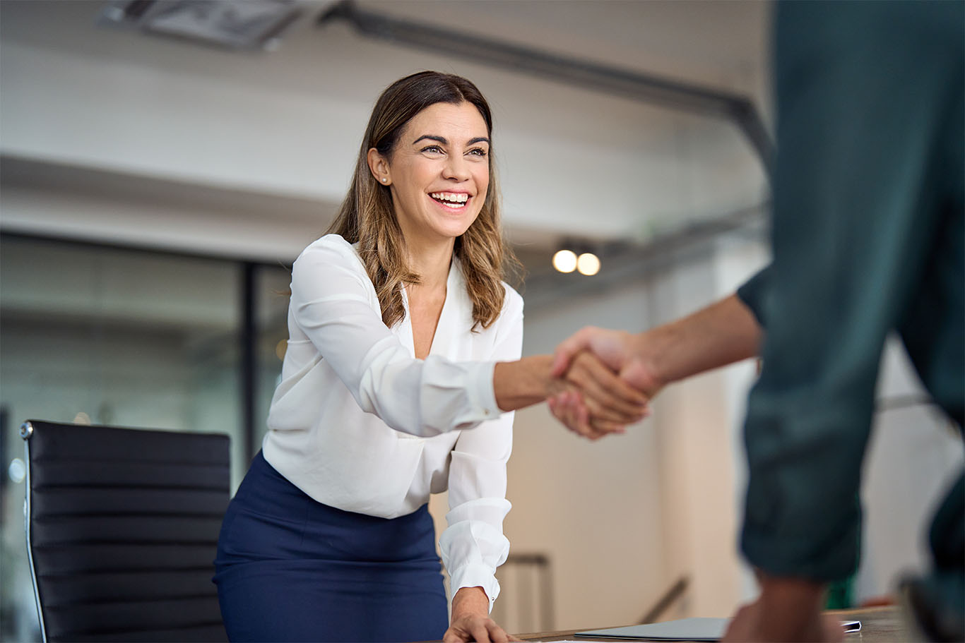 Professional woman shaking hands with co-worker to support leadership identity article