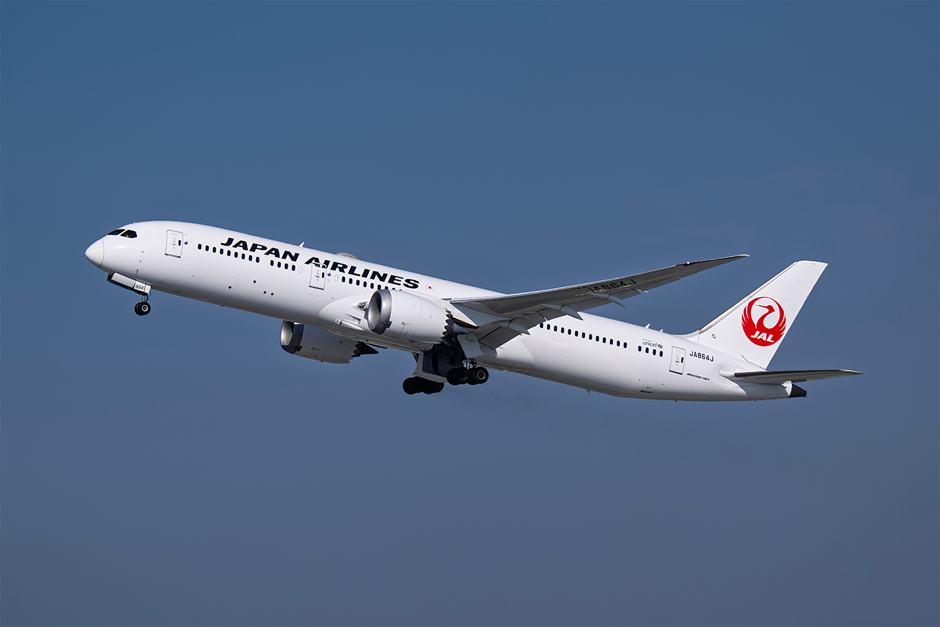 Japan Airlines Boeing 787 aircraft taking off against a clear blue sky